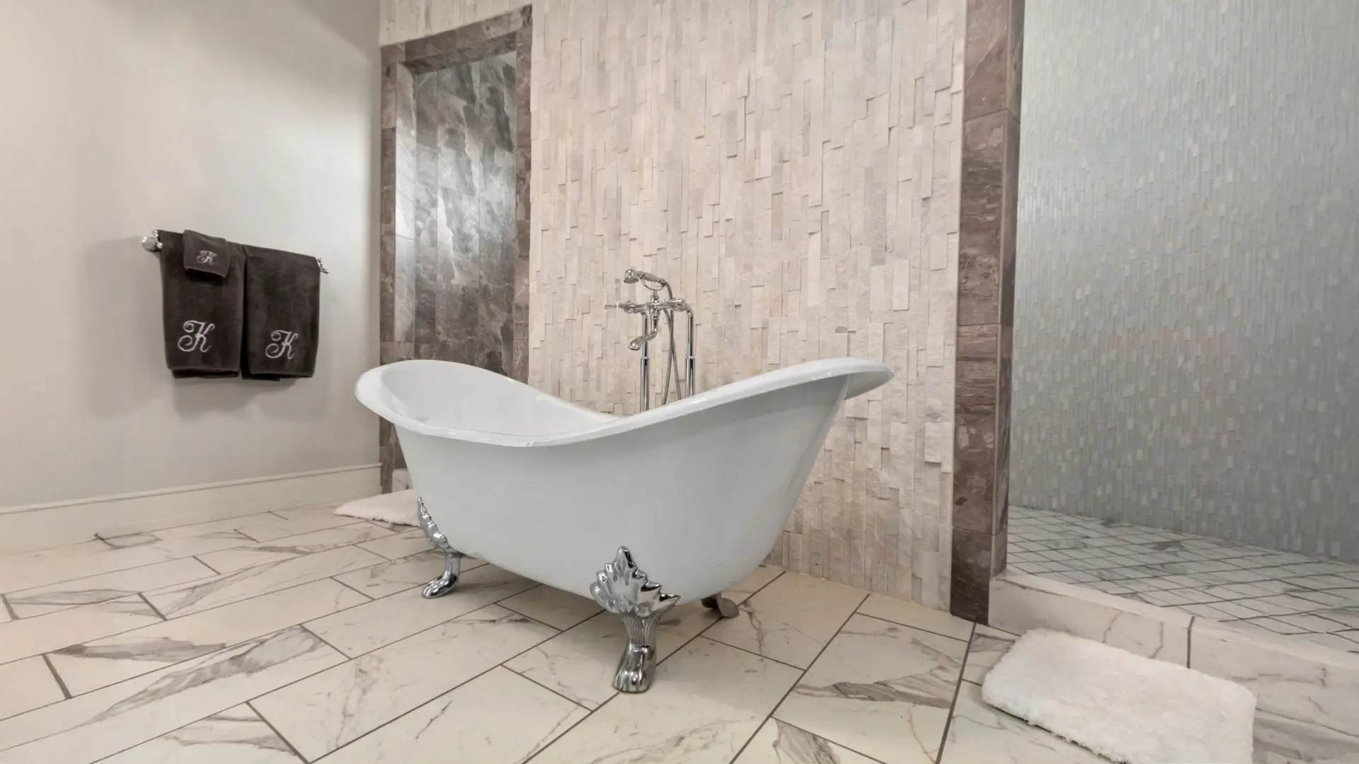 Elegant bathroom with wall to wall tile and tile flooring. A luxurious bath tub sits against the tile backsplash.
