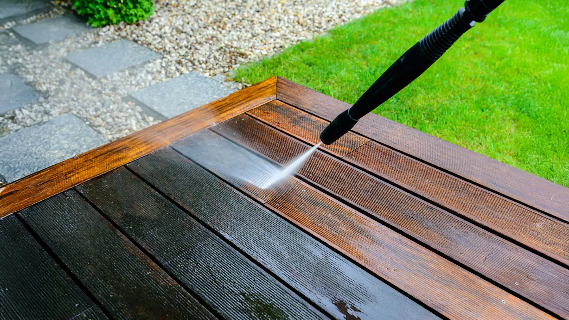 Cleaning terrace with a power washer - high water pressure cleaner on wooden terrace surface.