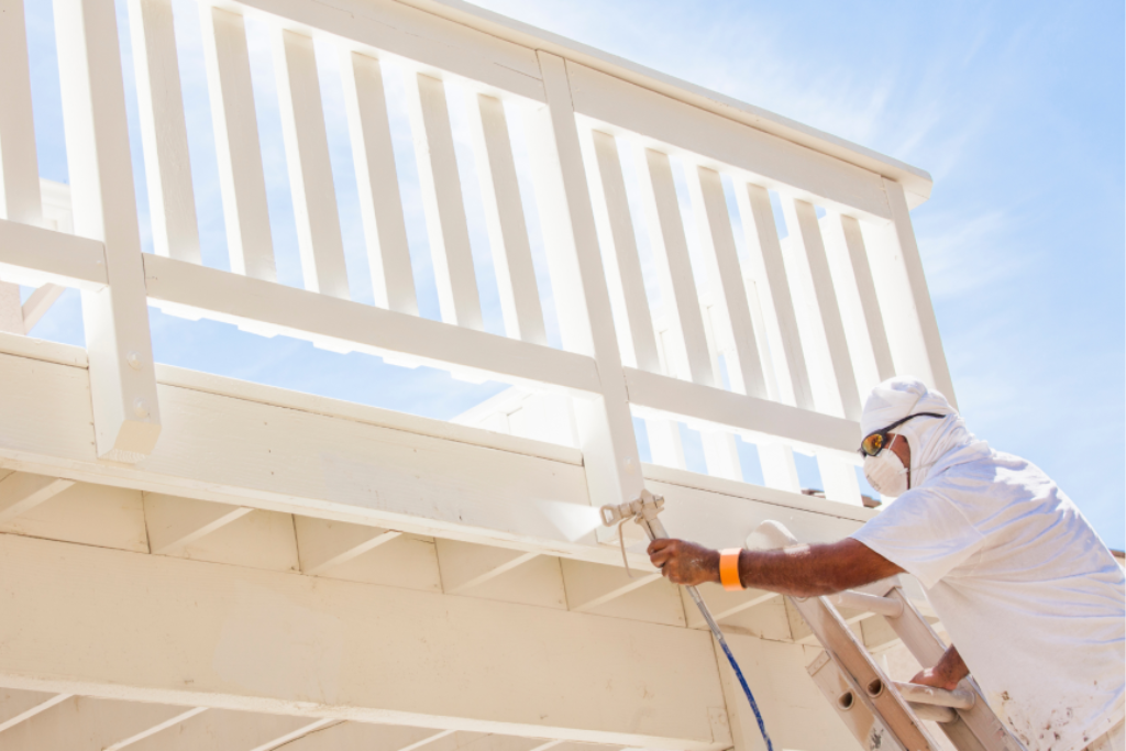Close-up of a painter's hand applying paint to a surface using a paintbrush in an exterior painting task.