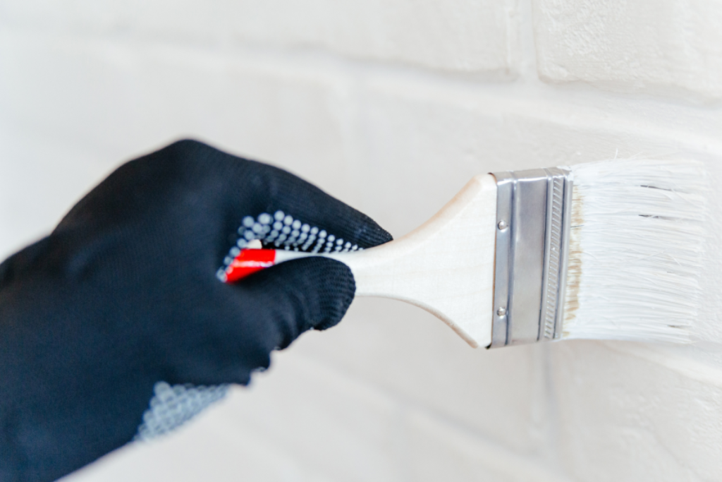 Painter using a paint sprayer for efficient exterior painting.
